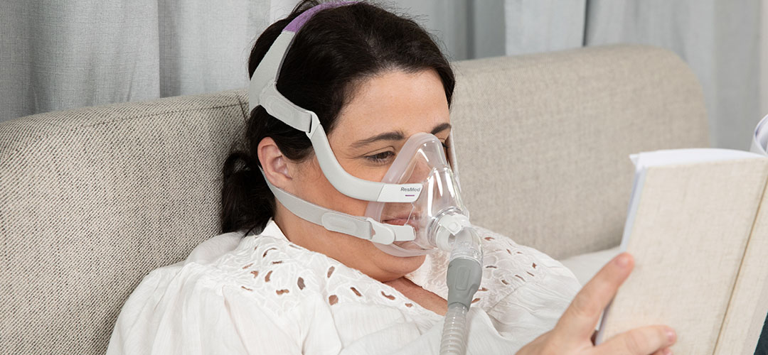 Woman wearing the ResMed F20 CPAP Mask for her version while reading