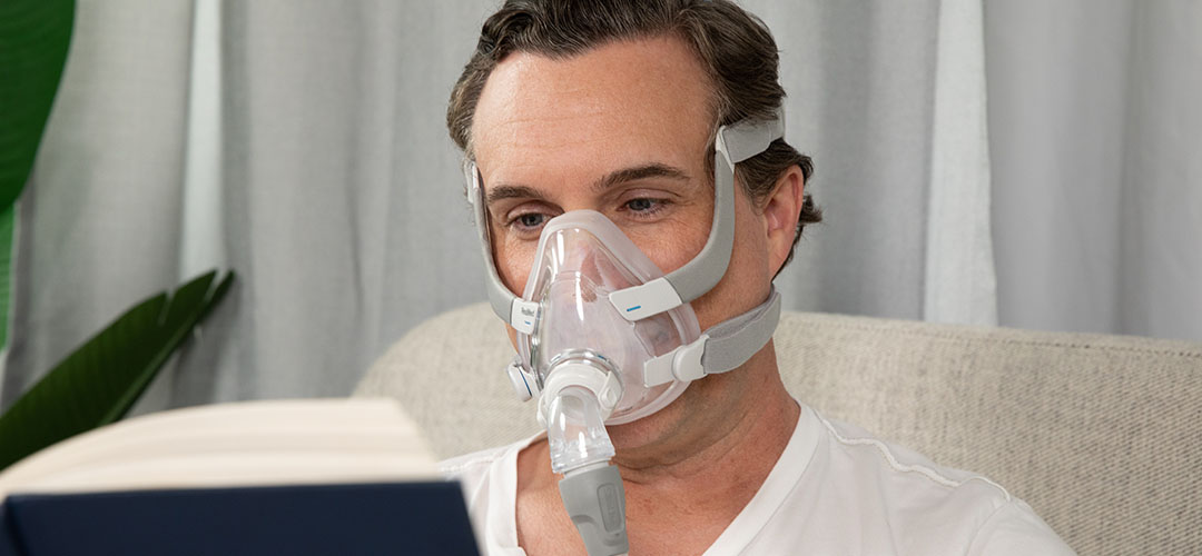 Man wearing the ResMed F20 Full Face CPAP Mask while reading