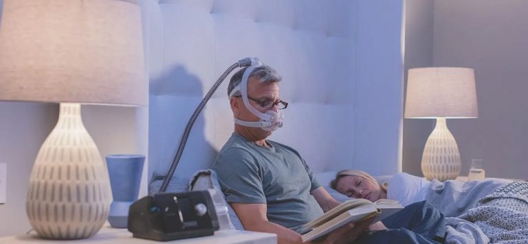 Man sitting in bed reading while wearing f30i cpap mask