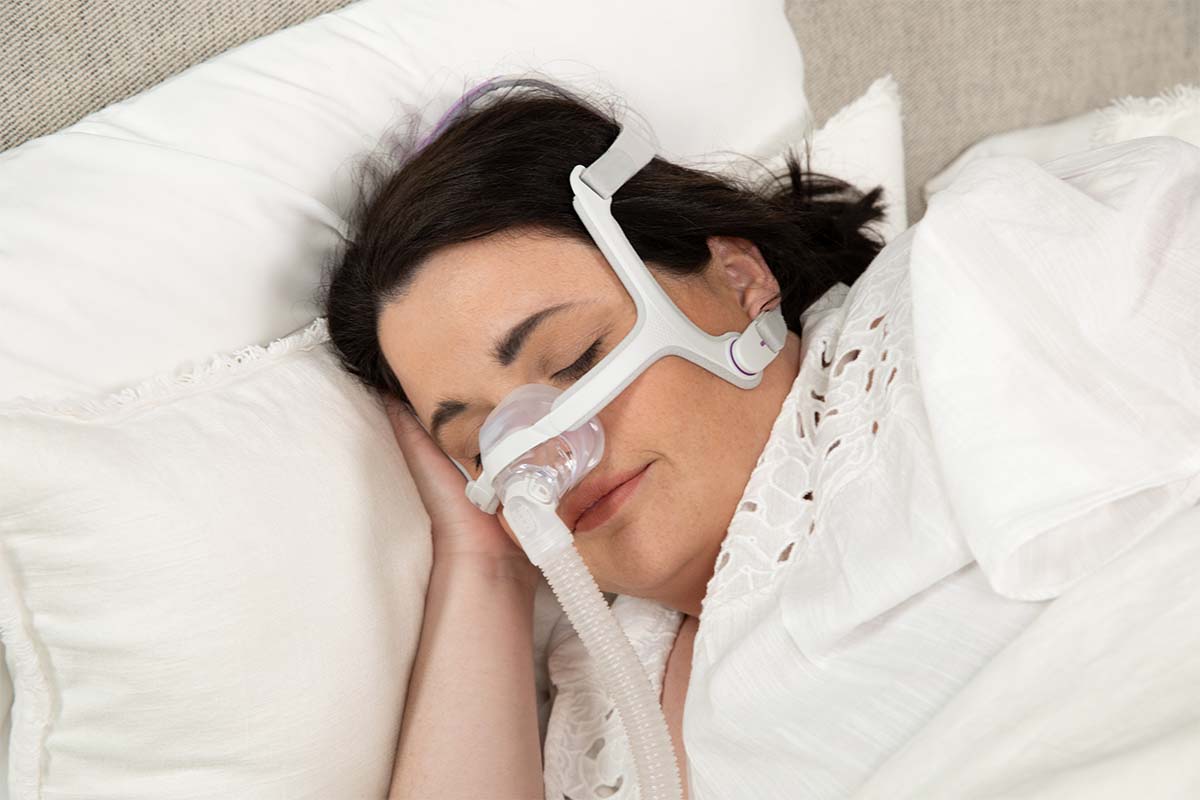 Woman wearing the AirFit n20 cpap mask in bed.