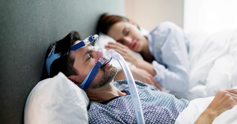 Man sleeping with a CPAP as a couple in bed