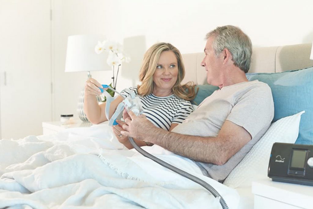 Man in bed shows F30 cpap mask to wife beside him