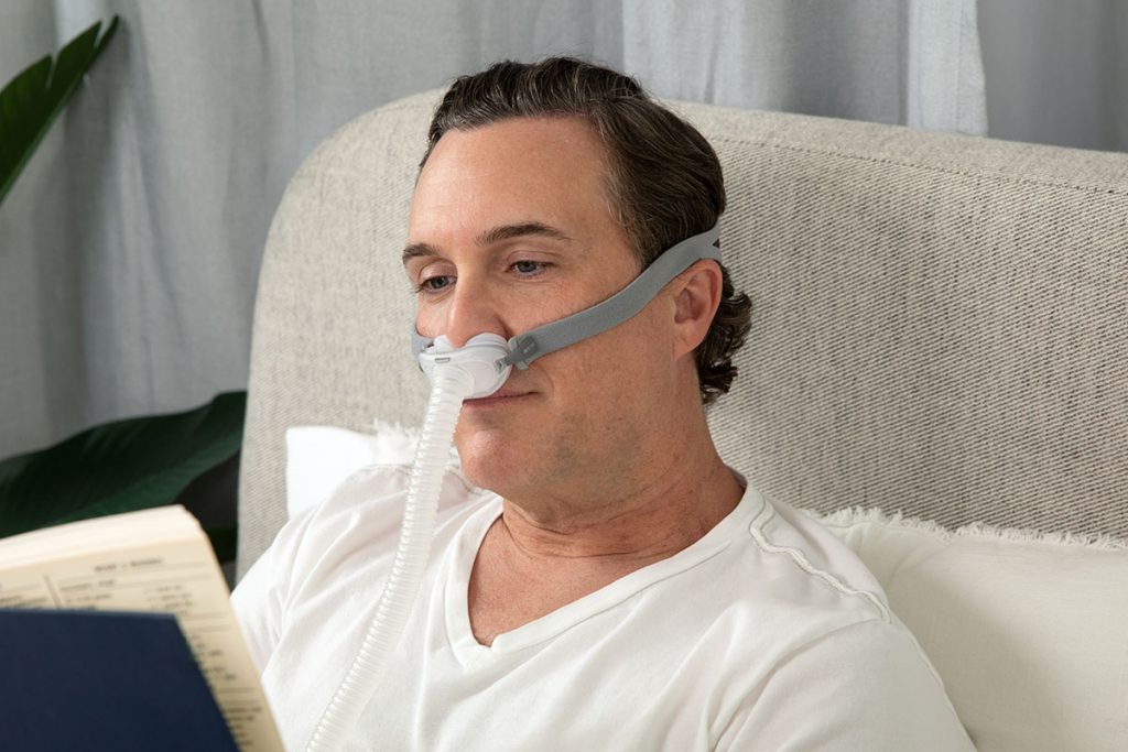 Man reads in bed while wearing AirFit p10