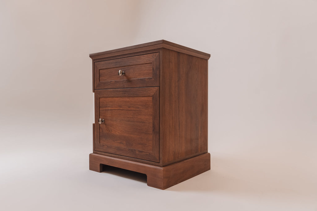 A three-quarter angled view of the Charleston Walnut CPAP nightstand, emphasizing its rich wood grain and sturdy base. The nightstand includes a top drawer, a lower storage cabinet, and side cutouts for CPAP hose access, blending traditional craftsmanship with modern functionality.