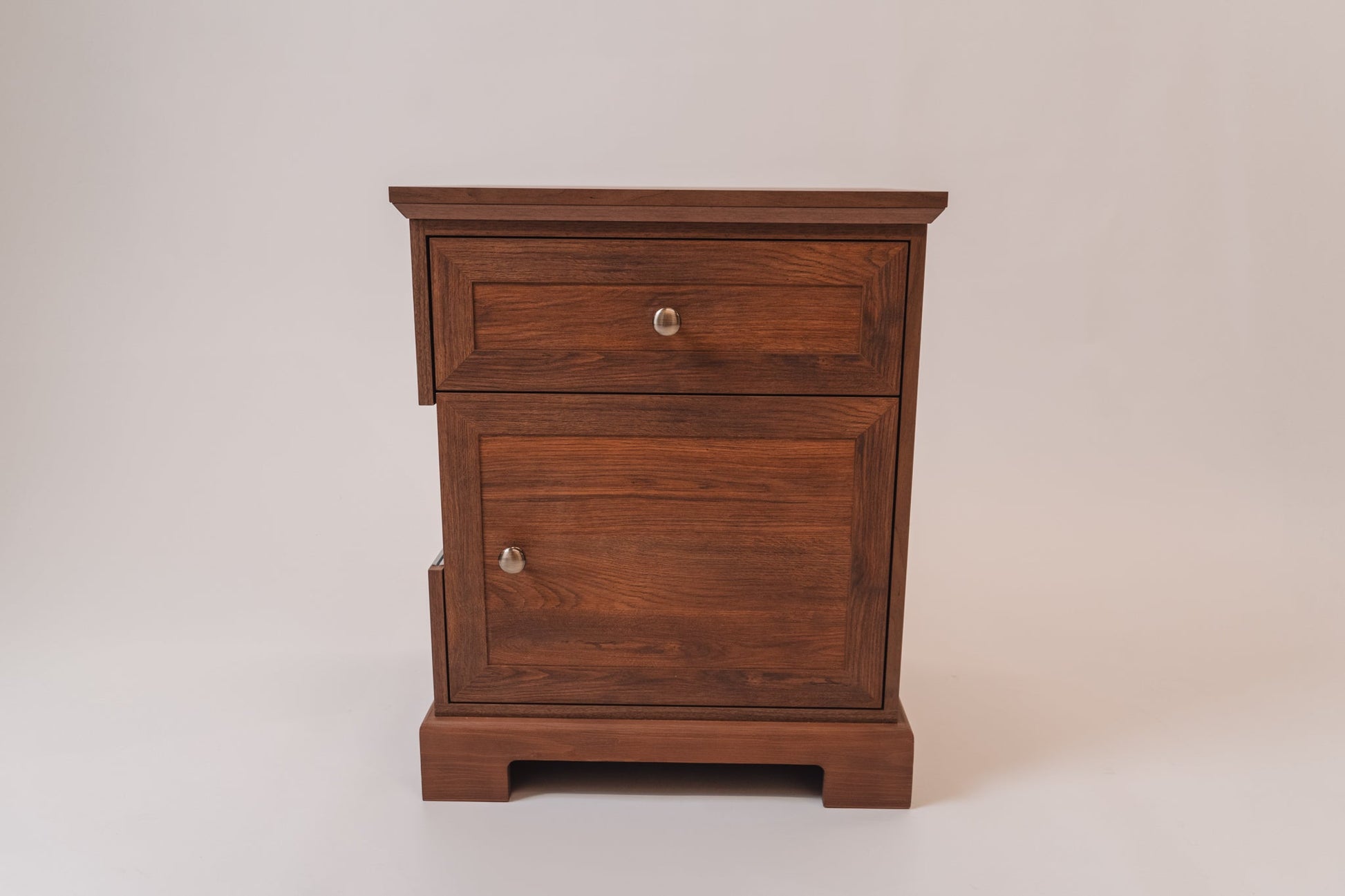 A closed CPAP nightstand in Charleston Walnut, showcasing its classic wooden panel design. It features a top drawer with a round metal knob and a lower storage compartment with a matching handle. The solid wood construction and deep walnut finish give it a timeless appearance.