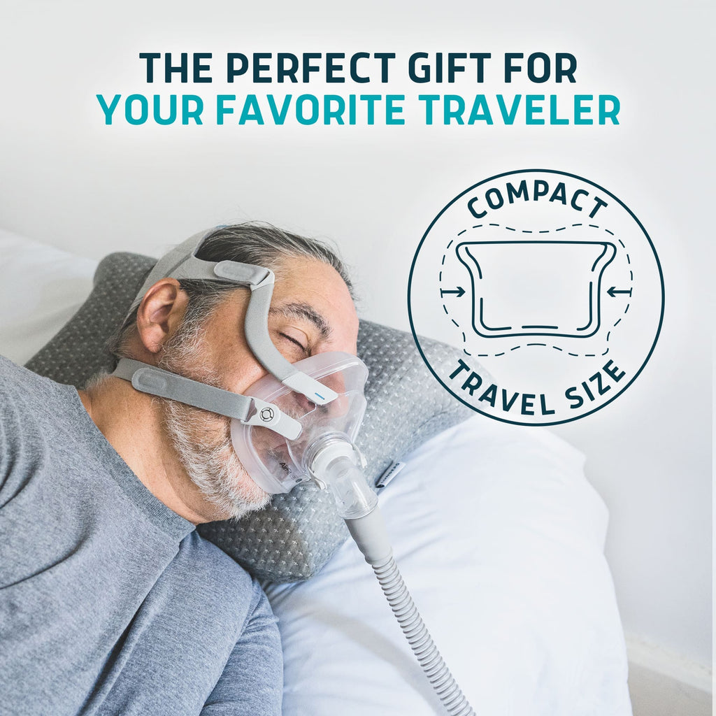 Man wearing a CPAP mask sleeping on a grey Lunderg travel-size memory foam pillow.