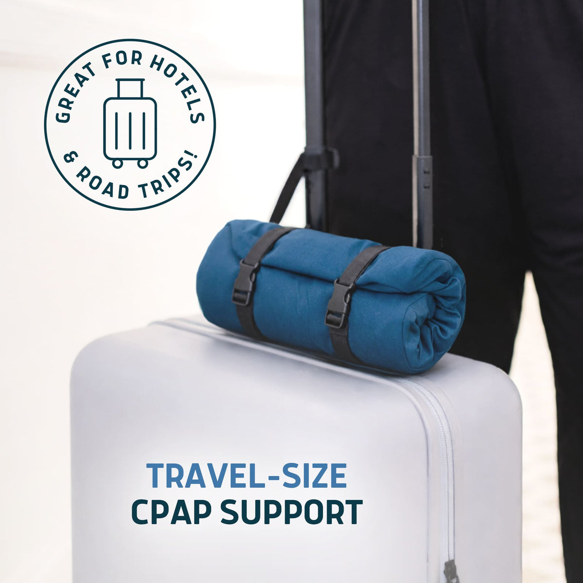 Blue Lunderg travel CPAP pillow rolled up and strapped to the handle of a white suitcase.