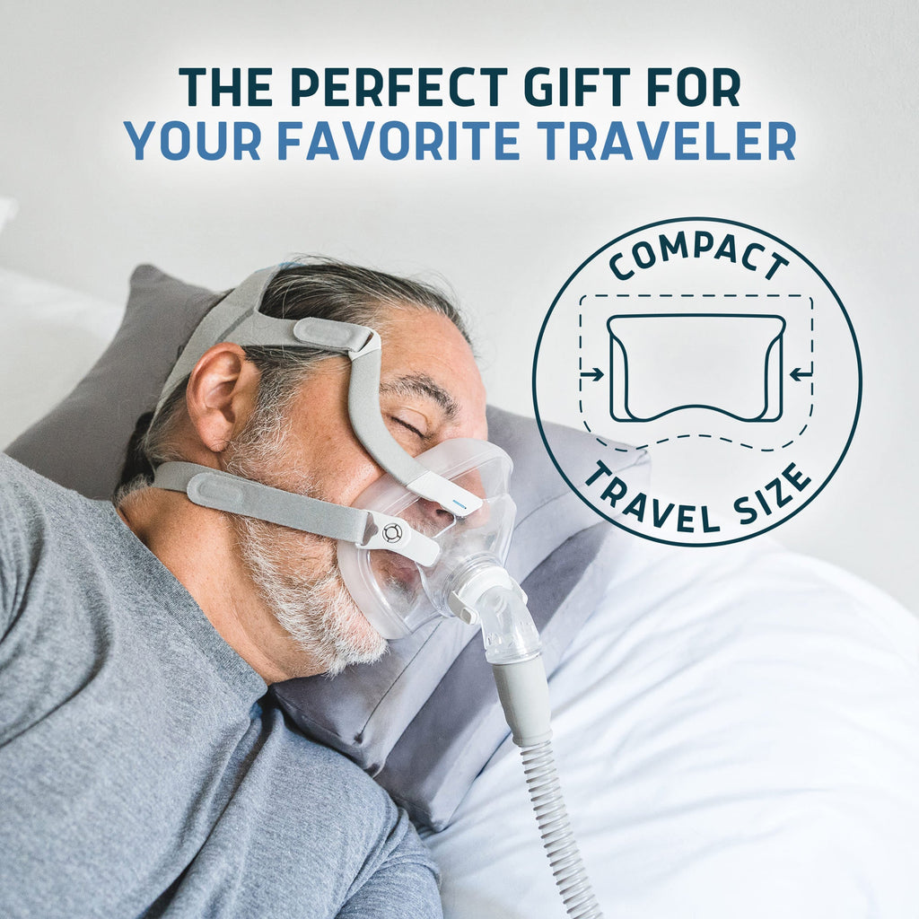 Man sleeping on a grey Lunderg travel CPAP pillow while wearing a full-face CPAP mask.