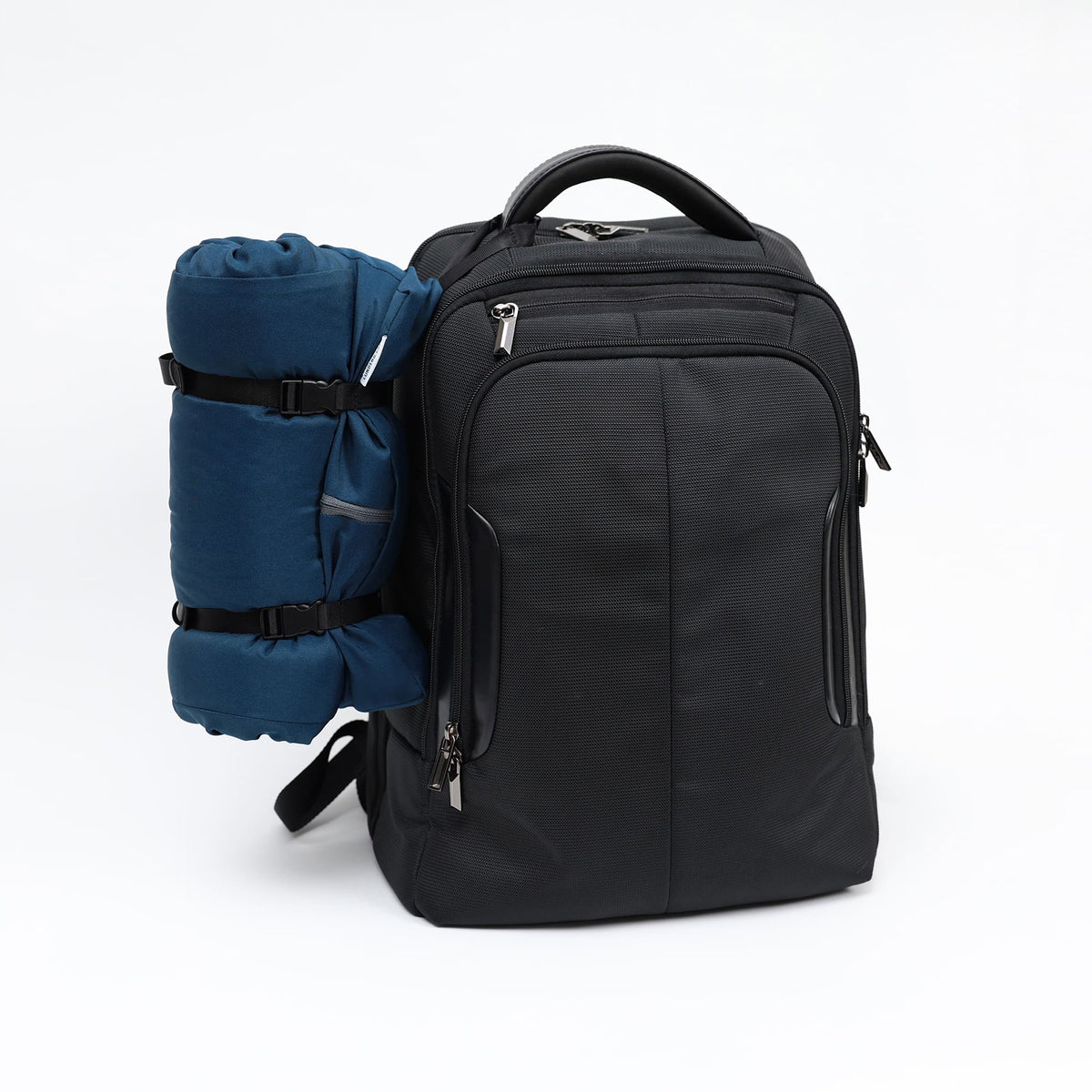 Lunderg travel CPAP pillow in blue, rolled and strapped to the side of a black backpack.