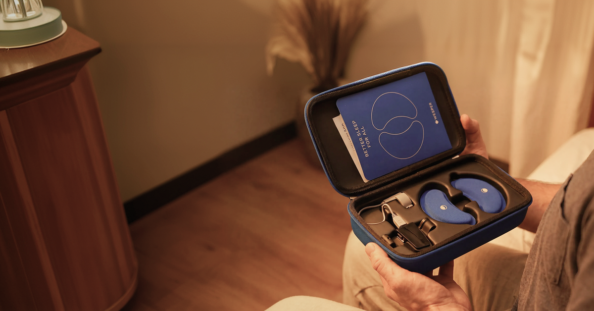 Person holding an open blue travel case containing a sleep mask and accessories.