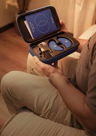A person holding an open blue hardshell carrying case containing blue sleep headphones and accessories.