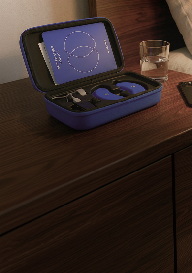 Blue Wesper sleep tracking device and charger in a hard shell carrying case on a wooden nightstand.