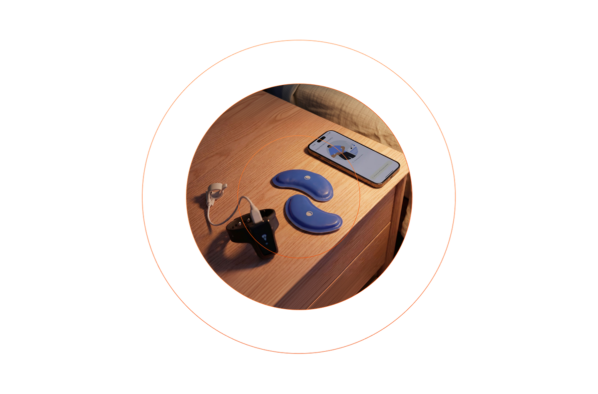 Two blue sleep apnea monitoring devices, a smartphone, and a charger on a wooden nightstand.