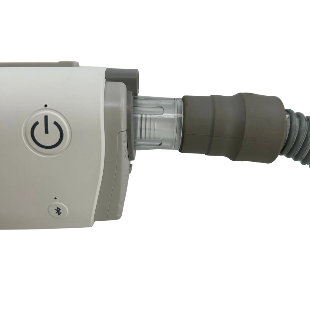 Close-up of a medical device with a gray power button, a clear connector, and a gray corrugated tube on a white background.
