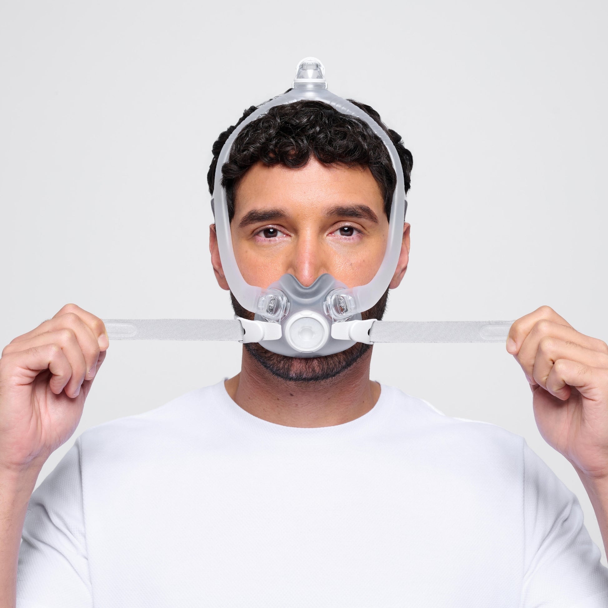a man wearing the airtouch f30i full face cpap mask adjusts the lower headgear straps