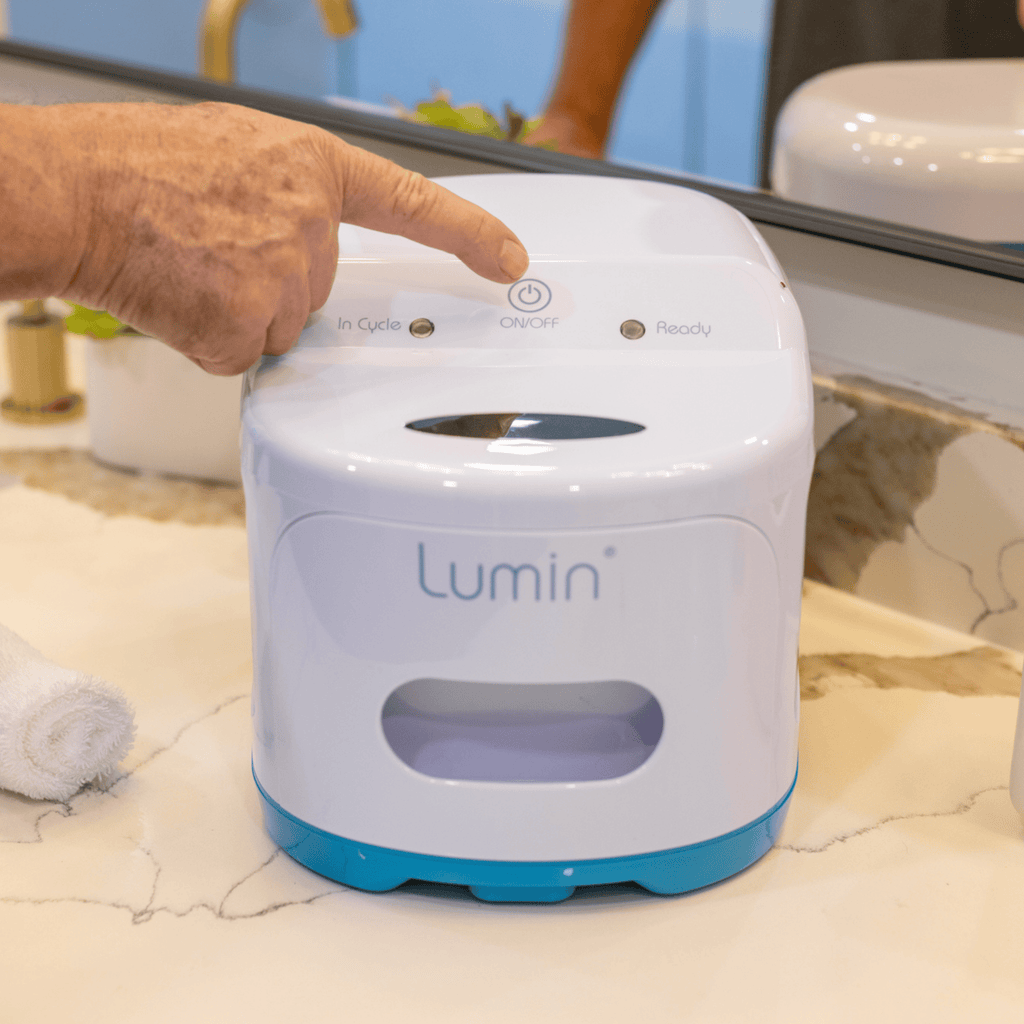 a hand reaches out to press the on/off button on the lumin, highlighting simple one button operation
