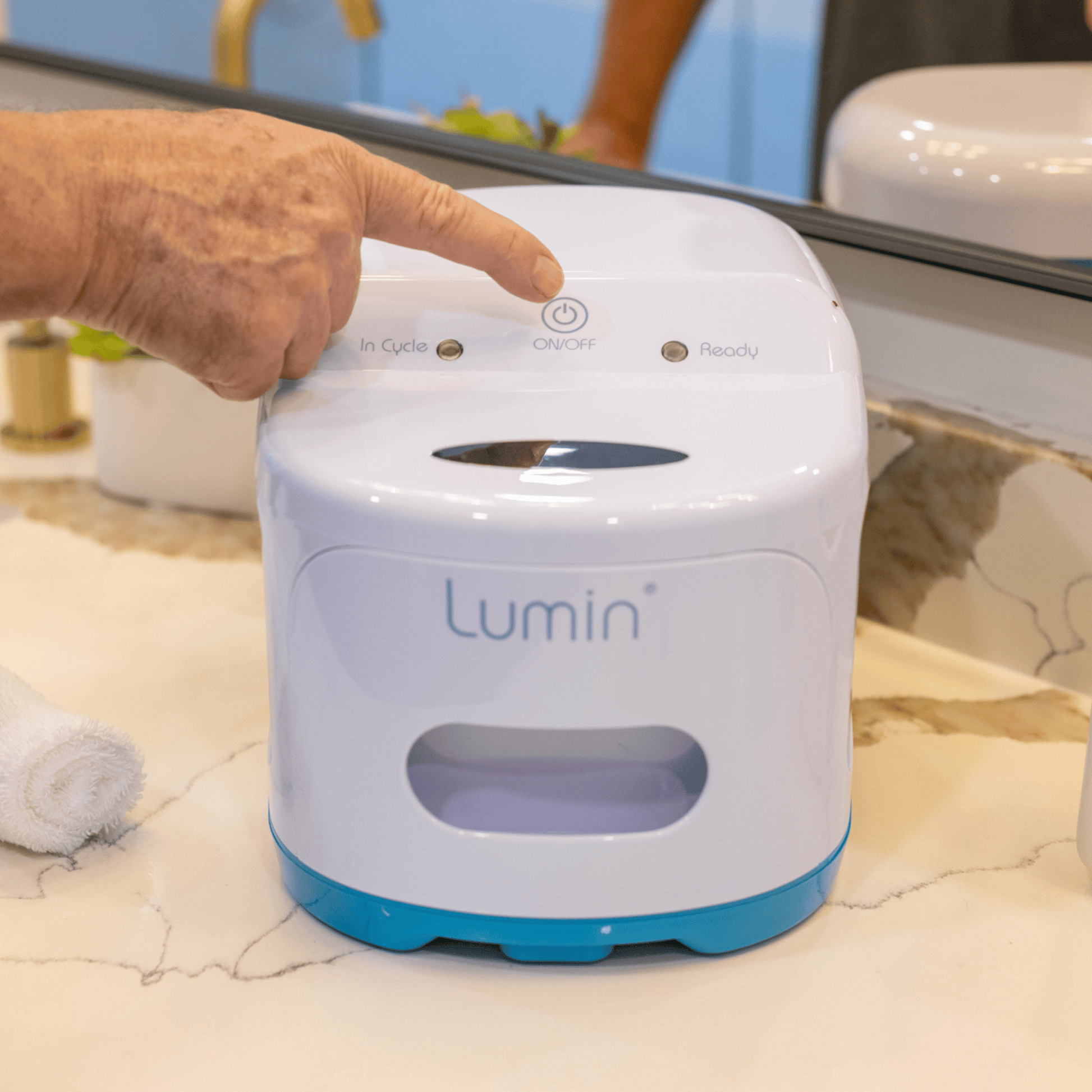 a hand reaches out to press the on/off button on the lumin, highlighting simple one button operation