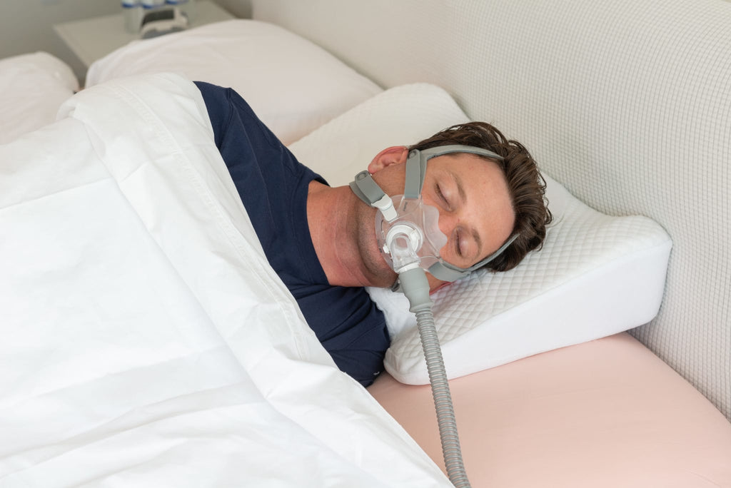 Man using Snugell Memory Foam CPAP Pillow with a CPAP mask, lying on his side for added neck and head support.
