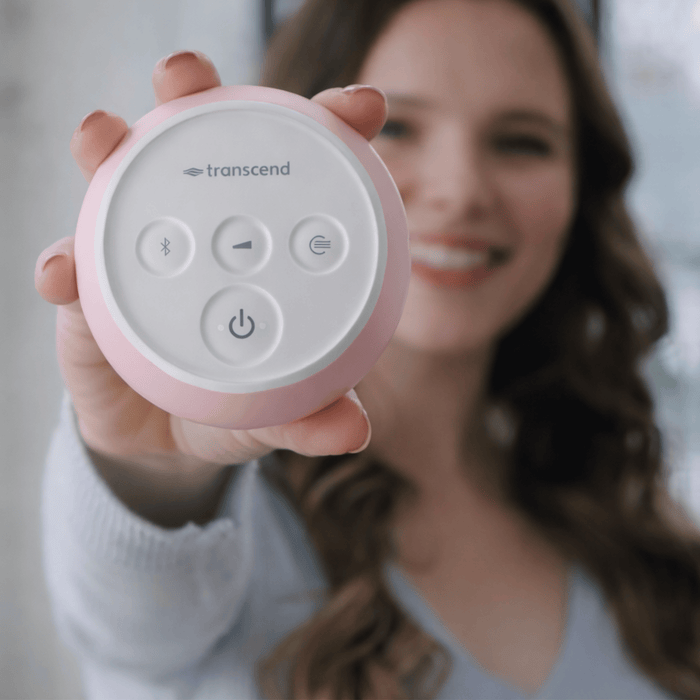 Person holding a pink Transcend Micro 510 Travel CPAP machine, showing the top control buttons.